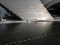 a photo of a big structure with water in it with people walking around it, and people walking about in front