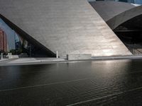 a photo of a big structure with water in it with people walking around it, and people walking about in front