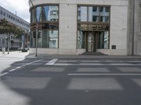 a crosswalk on the street that is close to a tall building with many windows