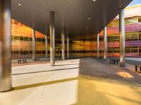 an empty courtyard that has colorful windows on it and benches lined in the background are on concrete