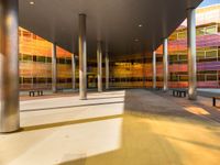 an empty courtyard that has colorful windows on it and benches lined in the background are on concrete