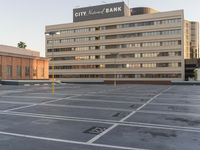 a building sitting in the middle of a parking lot on a street with lines painted in it