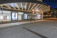 a picture of a building on the road at night with lights illuminating through glass and windows