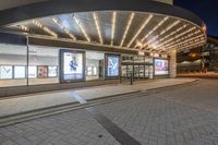 a picture of a building on the road at night with lights illuminating through glass and windows