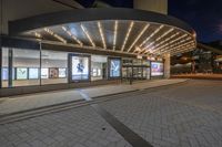 a picture of a building on the road at night with lights illuminating through glass and windows