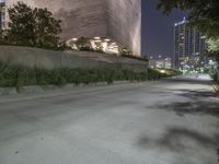 the sidewalk in front of a tall building with buildings along it at night or winter