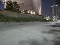 the sidewalk in front of a tall building with buildings along it at night or winter