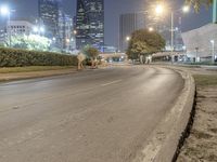 a man riding a skateboard on the side of a road at night with skyscrapers behind him