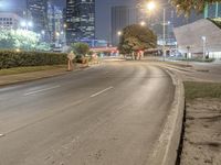 a man riding a skateboard on the side of a road at night with skyscrapers behind him