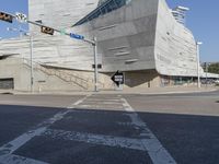 an empty, empty city street with a traffic light, and a curved building made up from concrete