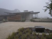 a driveway with a large bench sitting on it's side in the middle of a foggy yard