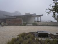 a driveway with a large bench sitting on it's side in the middle of a foggy yard