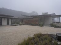 a driveway with a large bench sitting on it's side in the middle of a foggy yard