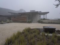 a driveway with a large bench sitting on it's side in the middle of a foggy yard