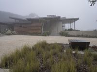 a driveway with a large bench sitting on it's side in the middle of a foggy yard