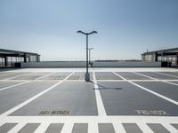 a parking lot with a clock and street lights on top of it next to the ocean