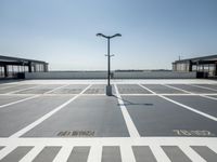 a parking lot with a clock and street lights on top of it next to the ocean