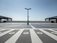 a parking lot with a clock and street lights on top of it next to the ocean