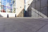 a skateboarder performs a trick on concrete pavement outside a building with many windows