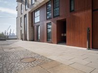 the man is walking in a doorway between two buildings that are made up of wood panels