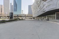 a sidewalk with no traffic on it leads to a large building with buildings behind it