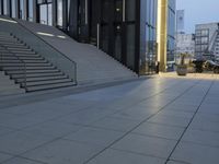 the entrance to a large glass building and steps leading up to it, with stairs in the ground on each side