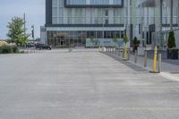 an empty parking lot with a yellow fire hydrant on the side of it, and a tall building in the background