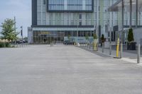 an empty parking lot with a yellow fire hydrant on the side of it, and a tall building in the background