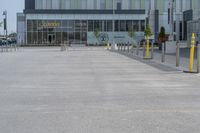 an empty parking lot with a yellow fire hydrant on the side of it, and a tall building in the background