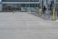 an empty parking lot with a yellow fire hydrant on the side of it, and a tall building in the background