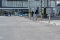 an empty parking lot with a yellow fire hydrant on the side of it, and a tall building in the background