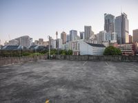 an empty parking lot with a bunch of buildings behind it and the skyline of downtown vancouver visible in the distance