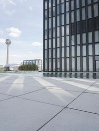 an empty pool in front of a very large building with black windows and glass walls