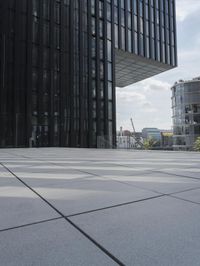 an empty pool in front of a very large building with black windows and glass walls