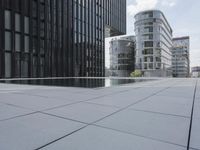 an empty pool in front of a very large building with black windows and glass walls