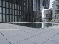 an empty pool in front of a very large building with black windows and glass walls