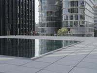 an empty pool in front of a very large building with black windows and glass walls