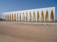 a large building with golden colored columns in front of the water on a beach area