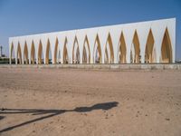 a large building with golden colored columns in front of the water on a beach area