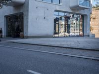 a city street with an empty sidewalk next to a building with glass doors on both sides