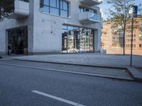 a city street with an empty sidewalk next to a building with glass doors on both sides
