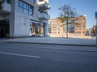 a city street with an empty sidewalk next to a building with glass doors on both sides