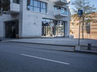 a city street with an empty sidewalk next to a building with glass doors on both sides