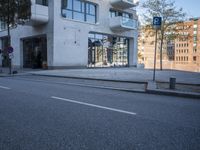 a city street with an empty sidewalk next to a building with glass doors on both sides
