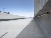 a concrete ramp next to some buildings with no people in the distance and a person sitting on the floor