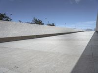 a concrete ramp next to some buildings with no people in the distance and a person sitting on the floor