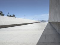 a concrete ramp next to some buildings with no people in the distance and a person sitting on the floor