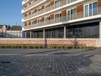 an empty courtyard has small plants growing on it and a brick wall near the building