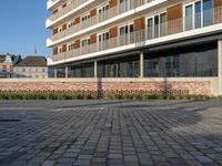 an empty courtyard has small plants growing on it and a brick wall near the building