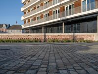 an empty courtyard has small plants growing on it and a brick wall near the building